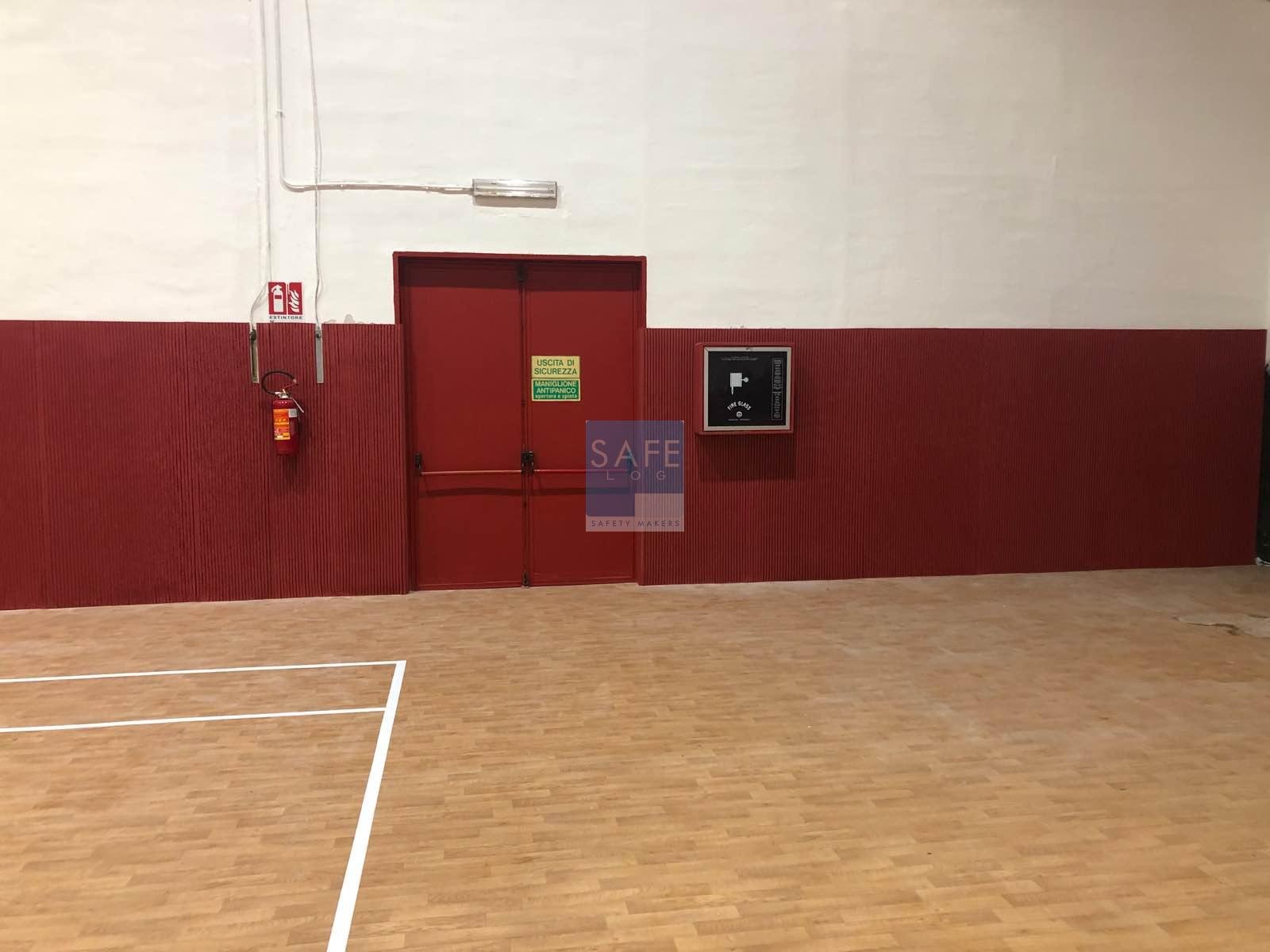 Protezioni antitrauma Tetris installate in impianto sportivo universitario, personalizzate nel colore istituzionale tramite scala RAL, per garantire sicurezza e coerenza visiva con il logo dell’università
